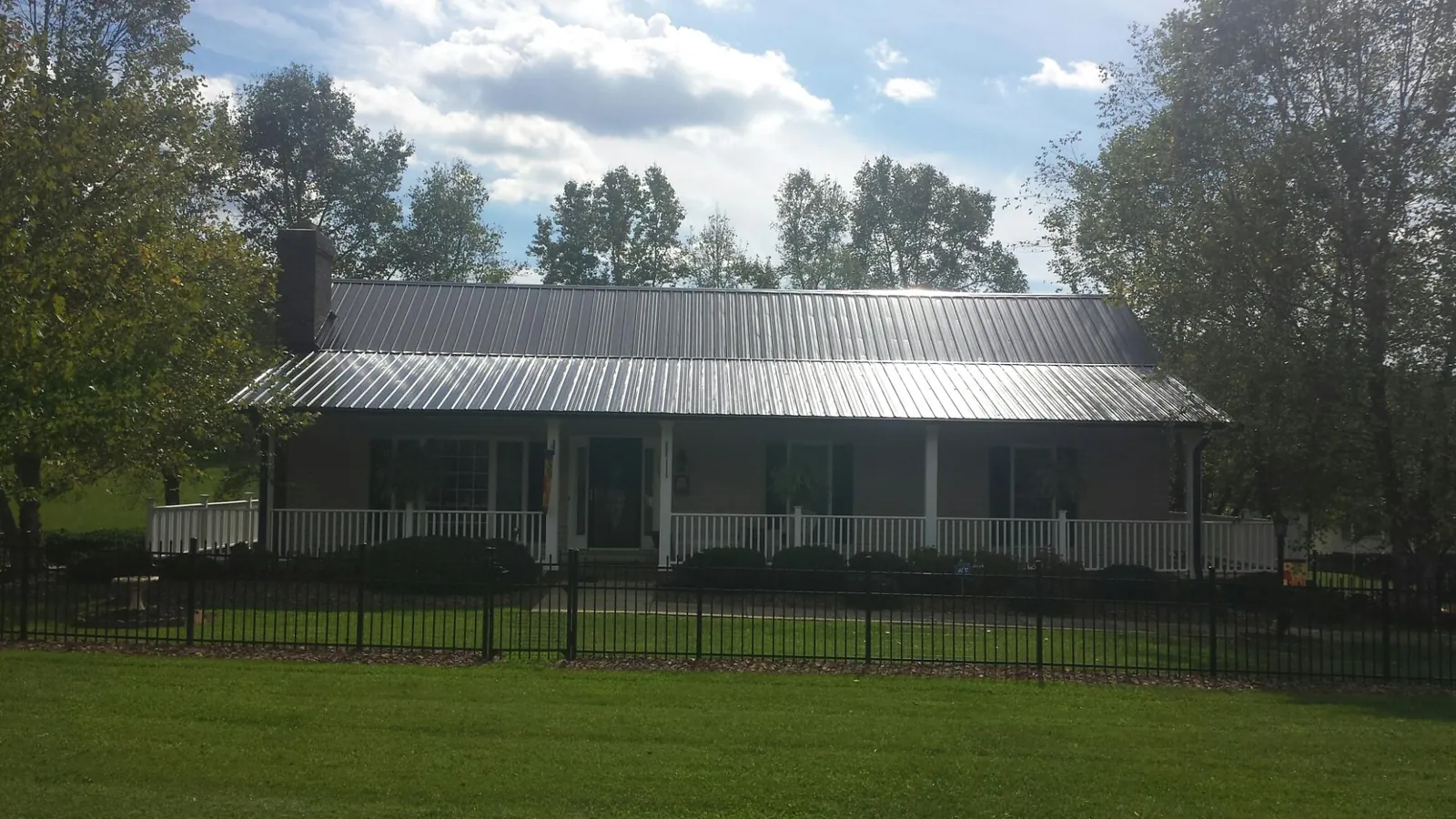 Gray metal roof on a brick ranch with a full width front porch in Moore