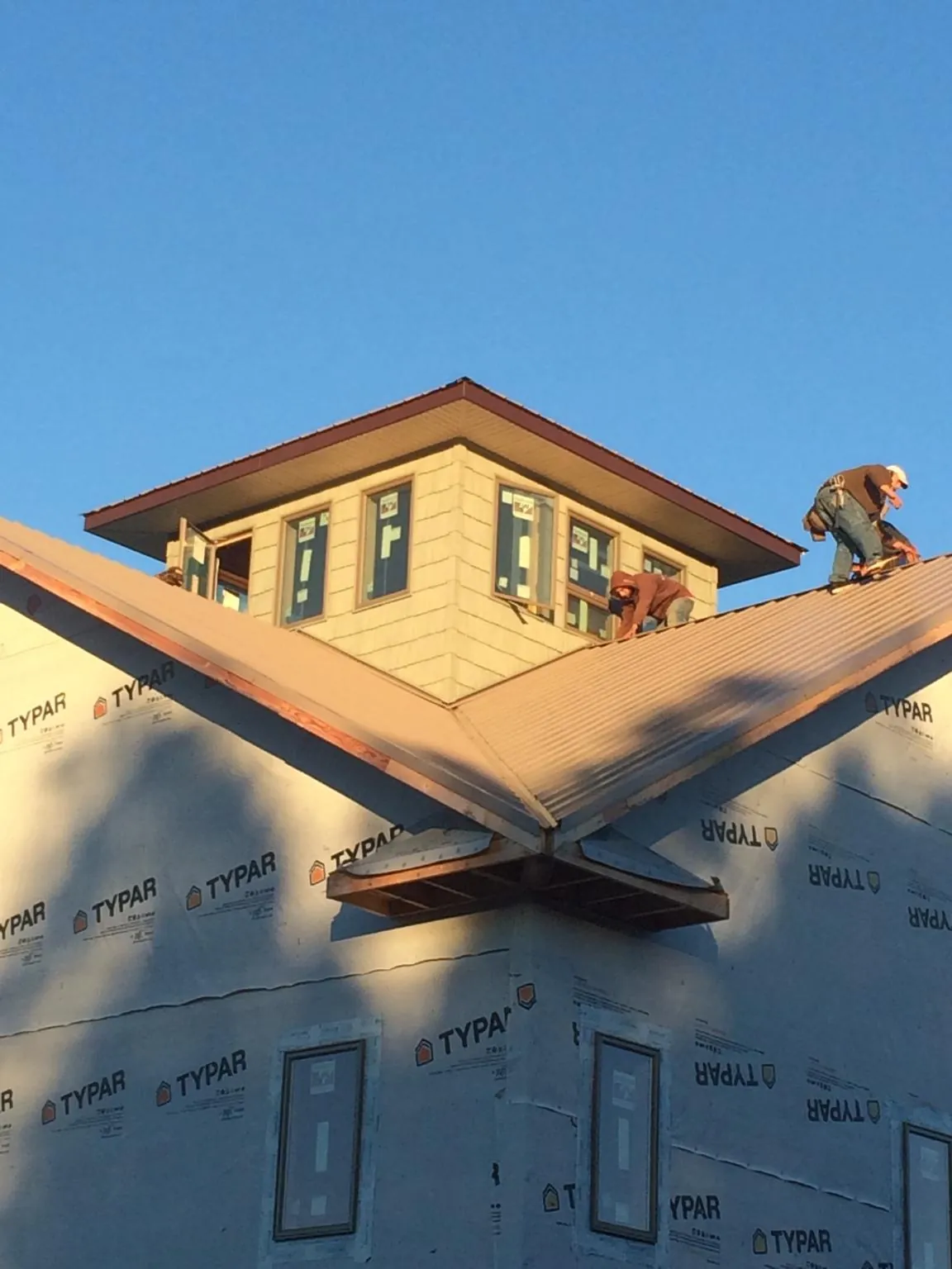Roofers working around a rooftop cupola on a new metal roof at sunset — Roof Waterproofing in Moore by Roofing Brothers